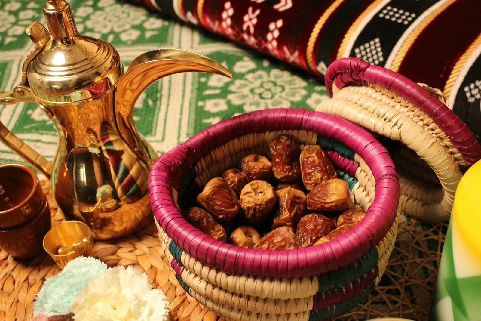 دلة قهوة عربية ذهبية بجانب سلة خوص فيها تمر